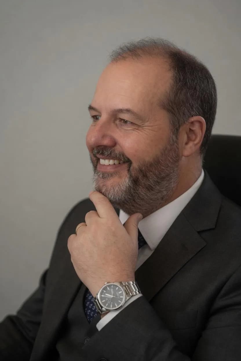Advogado de óculos, sentado, olhando para o lado e sorrindo, em cor